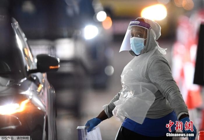 當(dāng)?shù)貢r(shí)間12月18日，英國政府公布的數(shù)據(jù)顯示，當(dāng)天英國新增奧密克戎毒株感染病例10059例。鑒于奧密克戎毒株感染病例激增，住院人數(shù)不斷上升，倫敦市長宣布倫敦進(jìn)入“重大事故”狀態(tài)。圖為倫敦的一個(gè)免下車檢測中心，一名醫(yī)務(wù)工作者正準(zhǔn)備對(duì)司機(jī)進(jìn)行核酸檢測。