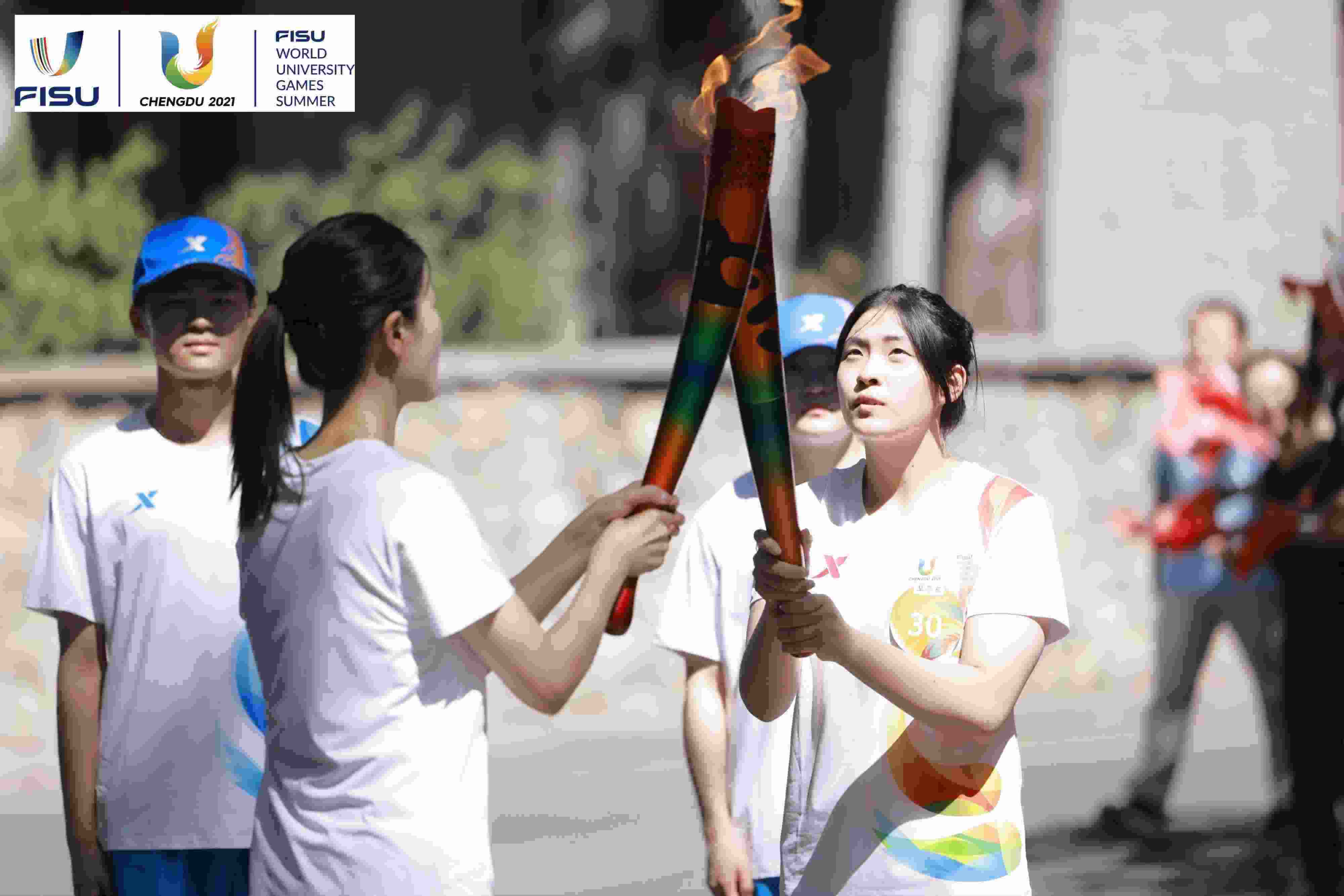 兩名大運會火炬手進行火炬?zhèn)鬟f。 圖片來源：成都大運會執(zhí)委會供圖