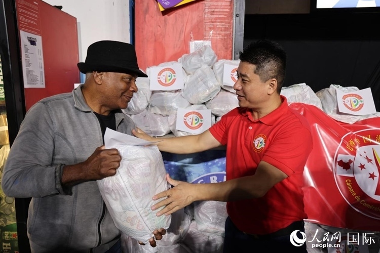 巴西中國浙江商會會長鄭俠茂向社區(qū)居民轉(zhuǎn)交捐贈物資。人民網(wǎng)記者 時元皓攝