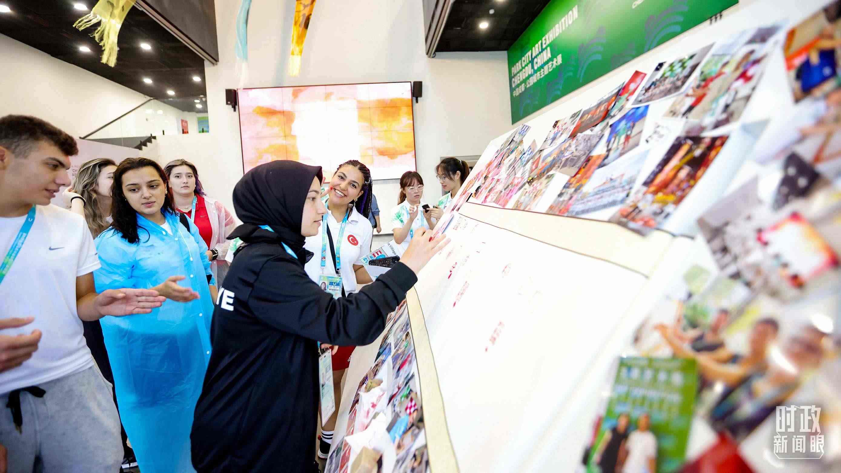 各國(guó)青年運(yùn)動(dòng)員正在參觀成都大運(yùn)村內(nèi)的“雪山下的公園城市，煙火里的幸福成都”主題藝術(shù)展。（總臺(tái)央視記者魏幫軍拍攝）