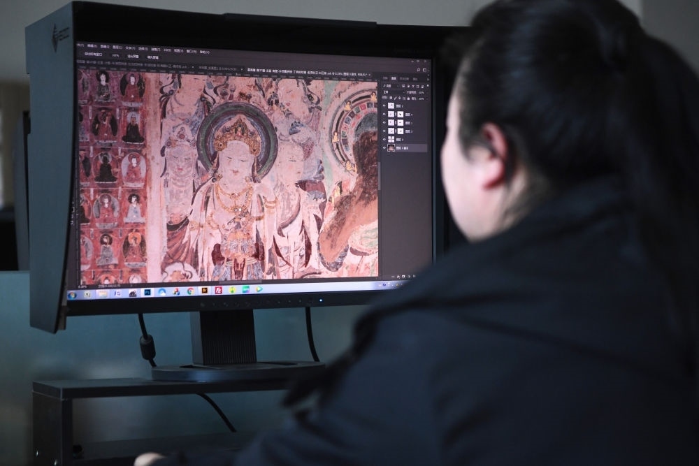 敦煌研究院文物數(shù)字化保護(hù)團(tuán)隊(duì)圖像處理人員年海麗在拼接壁畫圖像（2023年4月25日攝）。數(shù)字化探索為莫高窟的保護(hù)與傳承開辟了全新路徑，數(shù)字技術(shù)讓敦煌文物走出洞窟，跨出國門，走向“永久保存、永續(xù)利用”。新華社記者 陳斌 攝