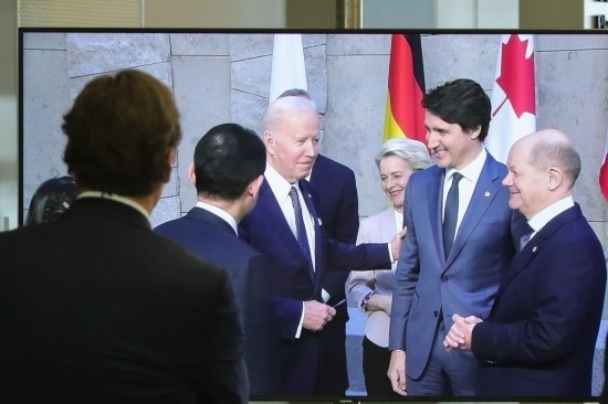 2022年3月24日，在比利時布魯塞爾的北約總部，一名男子觀看屏幕上美國總統(tǒng)拜登（右四）、歐盟委員會主席馮德萊恩（右三）、加拿大總理特魯多（右二）、德國總理朔爾茨（右一）出席七國集團峰會合影儀式的畫面。新華社記者鄭煥松攝