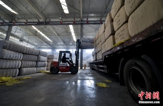 新疆喀什綜合保稅區(qū)，喀什啟路國際貿(mào)易有限公司的倉庫內(nèi)，工人正在裝載從塔吉克斯坦和烏茲別克斯坦進(jìn)口的棉花。劉新攝