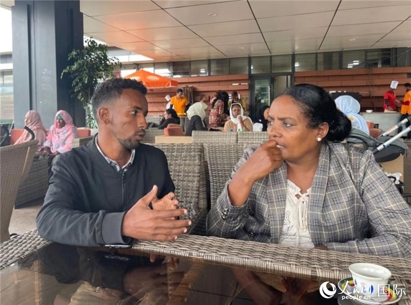 約漢斯（圖左）與德貝拉在友誼廣場咖啡廳交談。人民網記者 趙艷紅攝