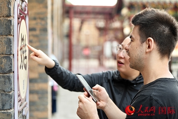 選手安德烈（俄羅斯）在老師指導(dǎo)下學(xué)習(xí)墻壁上張貼的生僻字。人民網(wǎng) 盧鵬宇攝