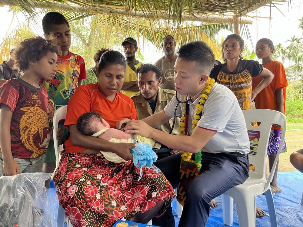 2023年8月5日，在巴布亞新幾內(nèi)亞中央省的一個(gè)村莊里，第12批援巴新中國(guó)醫(yī)療隊(duì)副隊(duì)長(zhǎng)、新生兒科副主任醫(yī)師劉振球?yàn)楫?dāng)?shù)貗雰郝?tīng)診檢查。新華社發(fā)（第12批援巴新中國(guó)醫(yī)療隊(duì)供圖）