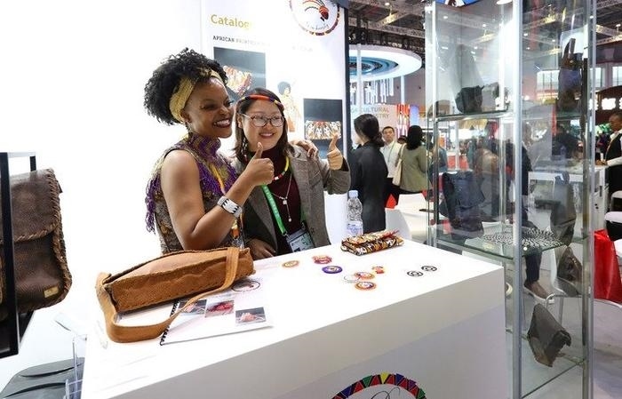 11月6日，一位參觀者（右）在第六屆進(jìn)博會(huì)國家展南非展臺(tái)試戴傳統(tǒng)首飾。