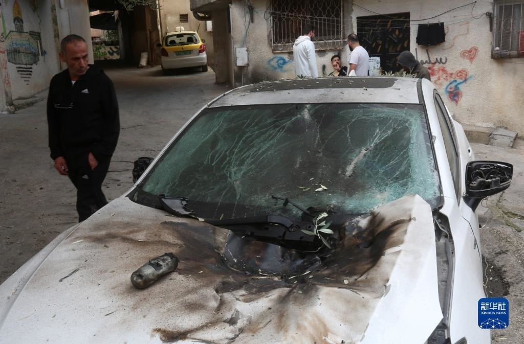 12月17日，在約旦河西岸城市圖勒凱爾姆附近的一處難民營，人們查看在沖突中損毀的車輛。新華社發(fā)（尼達(dá)爾·艾仕塔耶?dāng)z）