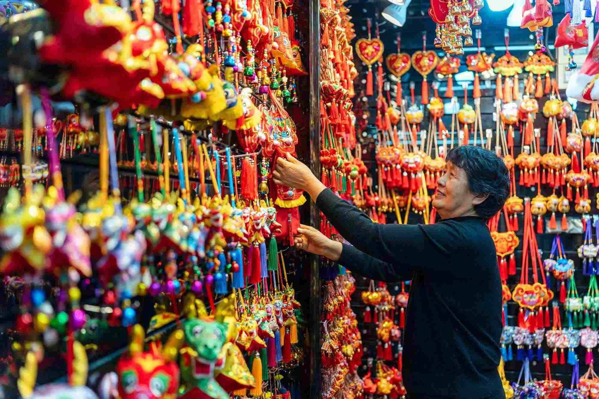 2023年12月11日，金華義烏國際商貿(mào)城，龍年喜慶用品掛滿攤位，顧客正在挑選中。