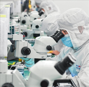 在位于武漢中國光谷的光電器件研發(fā)制造商——武漢光迅科技股份有限公司生產(chǎn)車間內(nèi)，技術(shù)人員在光模塊生產(chǎn)線作業(yè)（2023年4月11日攝）。程敏攝/本刊