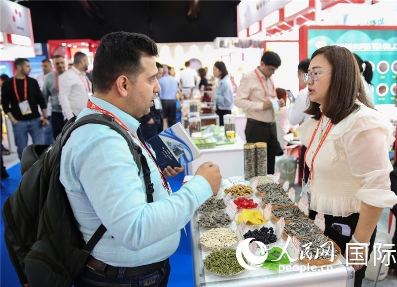 圖為一家中國(guó)干果參展企業(yè)代表與采購(gòu)商洽談。人民網(wǎng) 塔里克·易卜拉欣攝
