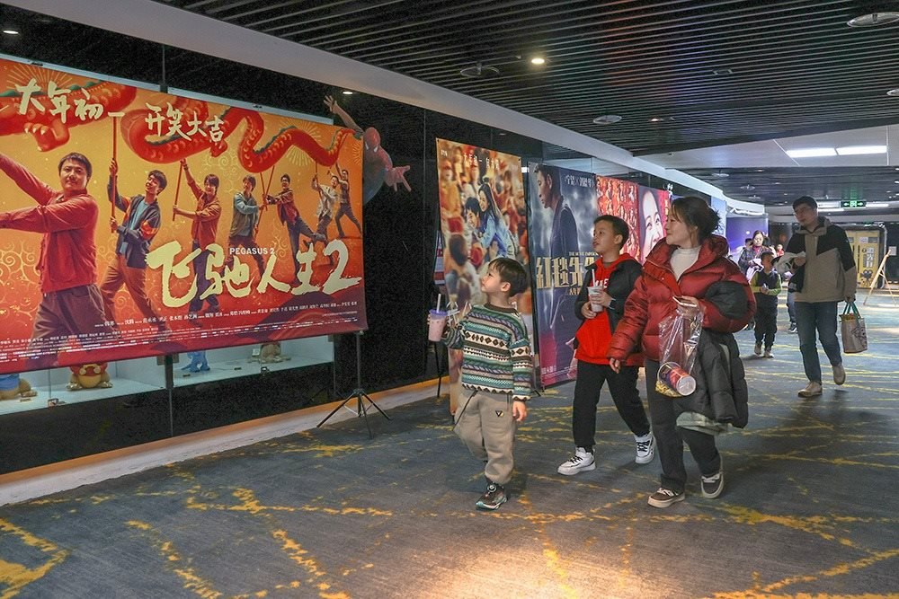△ 2024年2月16日，在江西贛州一家電影院，觀眾從春節(jié)檔電影的宣傳展板前走過(guò)。