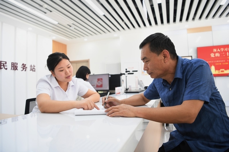 2023年5月23日，河北雄安新區(qū)容東片區(qū)南文營(yíng)社區(qū)居民（右）在社區(qū)便民服務(wù)站辦理業(yè)務(wù)。