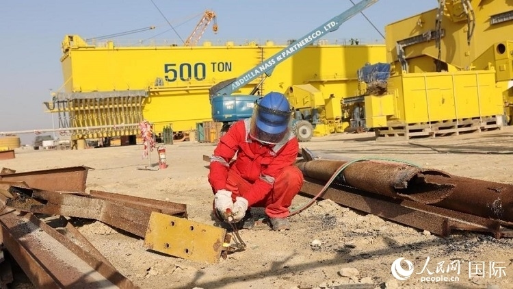 工人正在龍門吊吊裝現(xiàn)場切割金屬件。人民網(wǎng)記者管克江攝