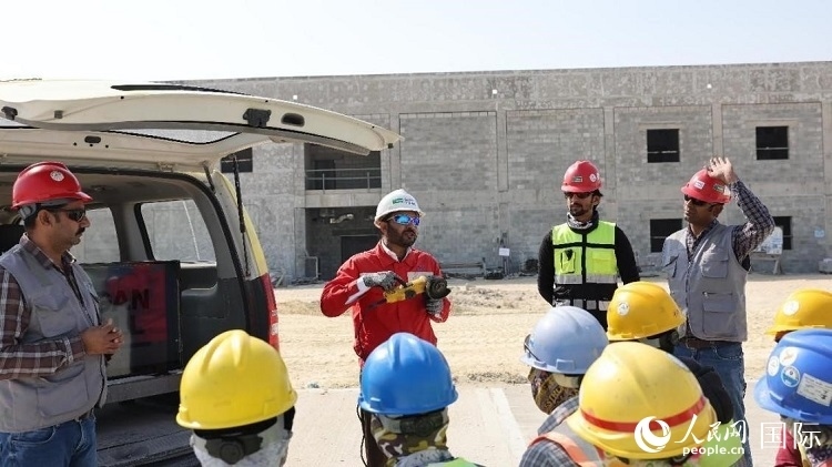 穆薩瓦爾(圖中紅衣人）現(xiàn)場演示工具操作規(guī)范。人民網(wǎng)記者 管克江攝