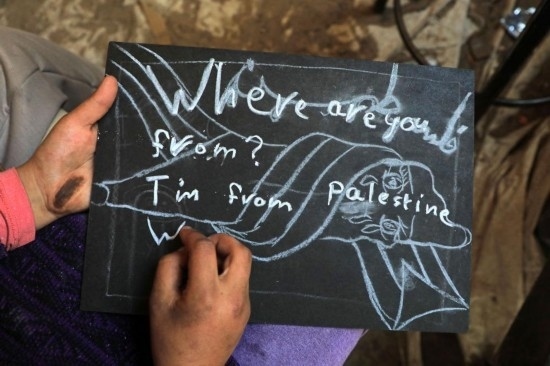 2023年12月28日，一名學(xué)生在加沙地帶南部城市拉法一所學(xué)校的臨時(shí)教室中寫(xiě)下“我來(lái)自巴勒斯坦”的字樣。新華社發(fā)（里澤克·阿卜杜勒賈瓦德攝）