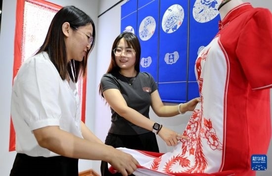 5月31日，在衡水市阜城縣一家剪紙工作室，游客在觀賞帶有剪紙元素的旗袍。
