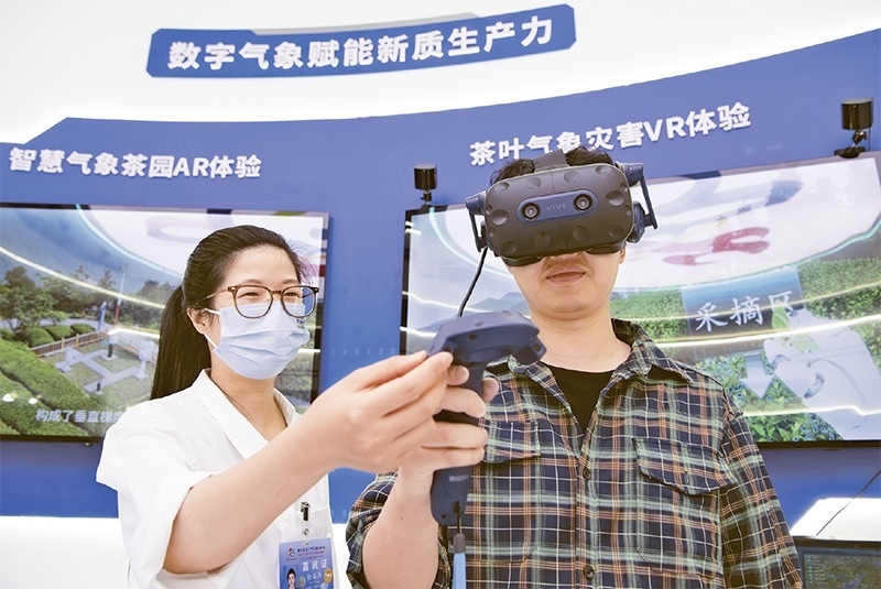 2024年5月23日，第七屆數字中國建設峰會現場體驗區(qū)在福州海峽國際會展中心向專業(yè)觀眾開放。本次現場體驗區(qū)圍繞本屆峰會主題“釋放數據要素價值，發(fā)展新質生產力”，設置“數字惠民”、“數字能力”、“數字基礎”、“數字生態(tài)”、“數字賦能”五大板塊。圖為一名觀眾（右）在數字氣象賦能新質生產力展臺上進行體驗。 新華社記者 魏培全/攝
