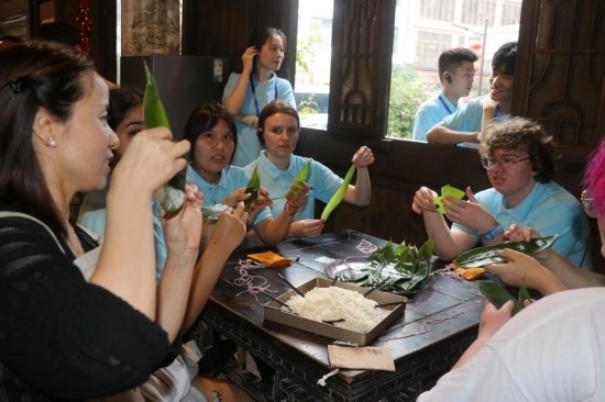 6月9日，美國青年代表在重慶永川松溉古鎮(zhèn)體驗包粽子。新華社記者 周思宇 攝