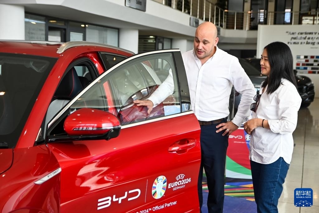 2024年5月29日，在馬耳他比爾基卡拉，馬耳他哈桑-扎米特汽車公司首席執(zhí)行官德古阿拉（左）介紹一輛比亞迪純電動汽車。新華社發(fā)（喬納森·博格 攝）