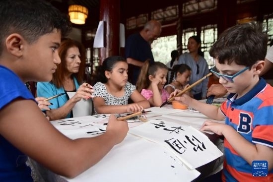 7月4日，在馬耳他桑塔露琪亞市的中國(guó)古典園林“靜園”，人們體驗(yàn)中國(guó)書(shū)法。新華社發(fā)（喬納森·博格 攝）