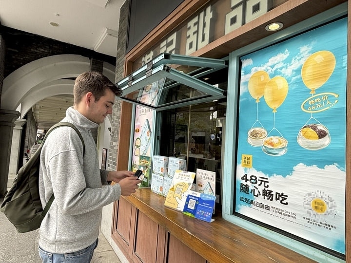 來自德國的留學(xué)生理查德在杭州西湖邊一家商鋪使用支付寶掃碼支付（2024年4月11日攝）。新華社發(fā)