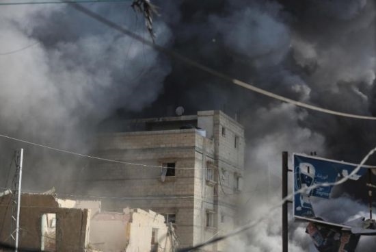 7月21日，在加沙地帶中部的努賽賴特難民營(yíng)，遭以軍空襲的建筑冒出滾滾濃煙。新華社發(fā)（馬爾萬(wàn)·達(dá)烏德攝）