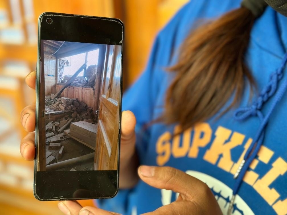 圖為7月17日拉毛東智在手機(jī)上找出地震后房屋受損的照片。新華社記者 張子琪 攝