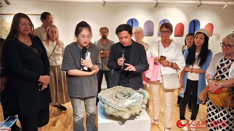 參展人、景德鎮(zhèn)陶瓷大學(xué)設(shè)計(jì)藝術(shù)學(xué)院副院長(zhǎng)余劍峰（中）向來賓介紹參展作品。人民網(wǎng)記者 殷淼攝