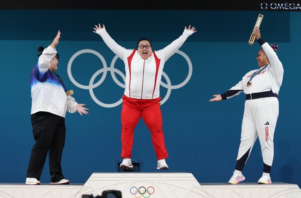 中國(guó)選手李雯雯（中）在巴黎奧運(yùn)會(huì)舉重女子81公斤以上級(jí)頒獎(jiǎng)儀式中登上領(lǐng)獎(jiǎng)臺(tái)（2024年8月11日攝）。新華社記者 楊磊 攝
