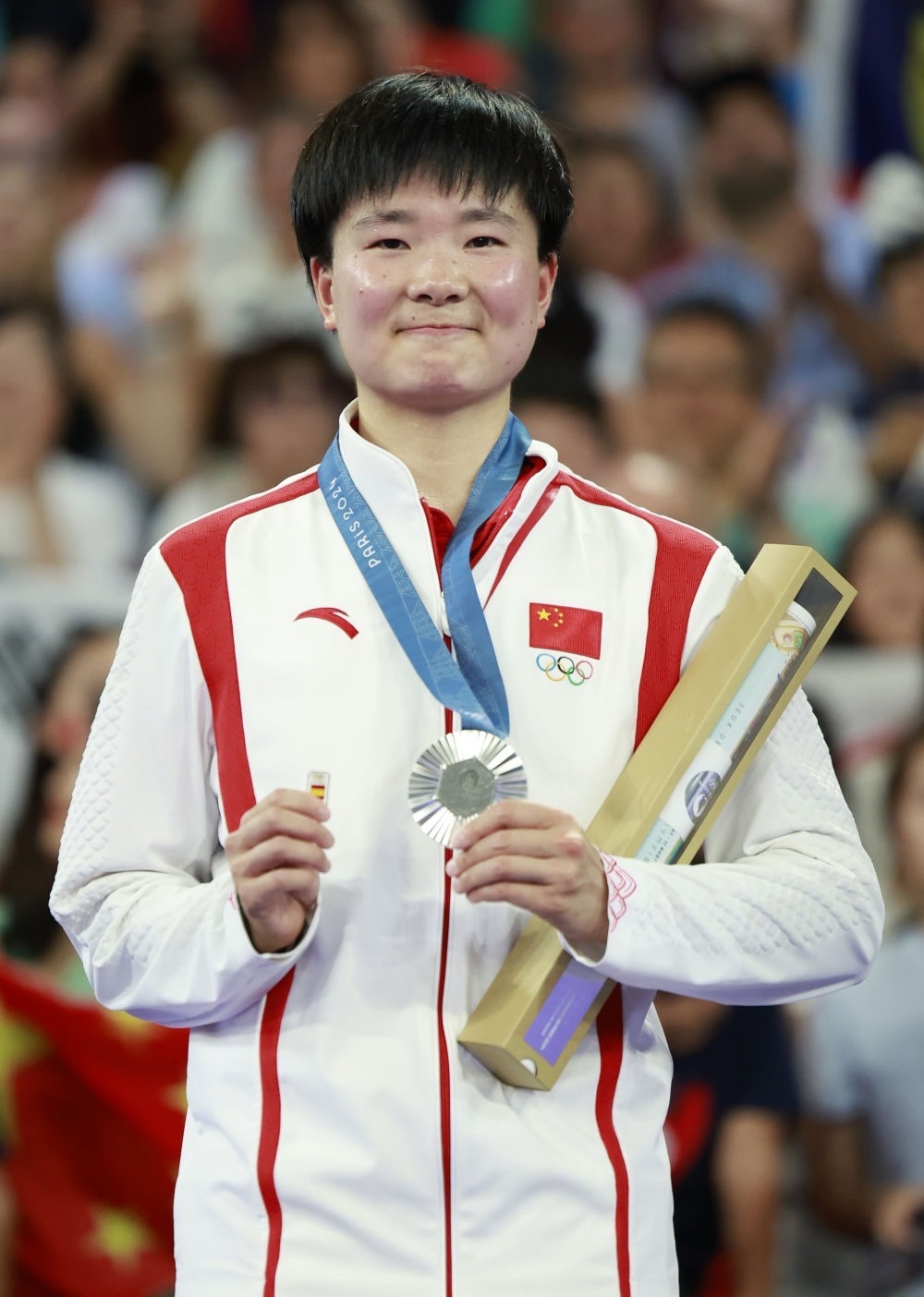巴黎奧運(yùn)會(huì)羽毛球女子單打亞軍、中國(guó)選手何冰嬌在頒獎(jiǎng)儀式上一手握著銀牌，一手握著西班牙奧委會(huì)徽章（2024年8月5日攝）。新華社記者 任正來(lái) 攝