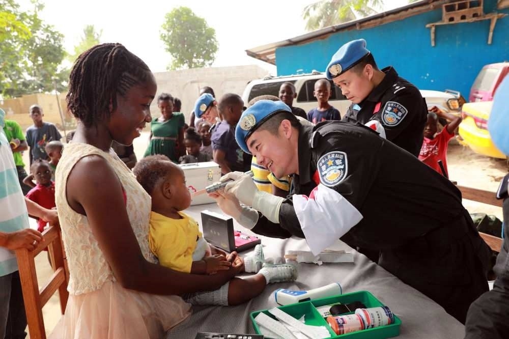 2017年12月28日，在利比里亞蒙羅維亞，中國維和警察防暴隊醫(yī)療人員為兒童做口腔檢查。