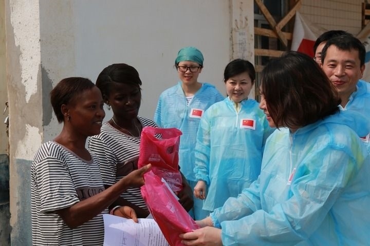 2015年4月4日，在位于塞拉利昂首都弗里敦市郊的中塞友好醫(yī)院埃博拉診療中心，中國(guó)第四批援塞醫(yī)療隊(duì)副隊(duì)長(zhǎng)邵蔚（右前）向被治愈的埃博拉出血熱患者贈(zèng)送禮物。新華社發(fā)（祖榮強(qiáng) 攝）