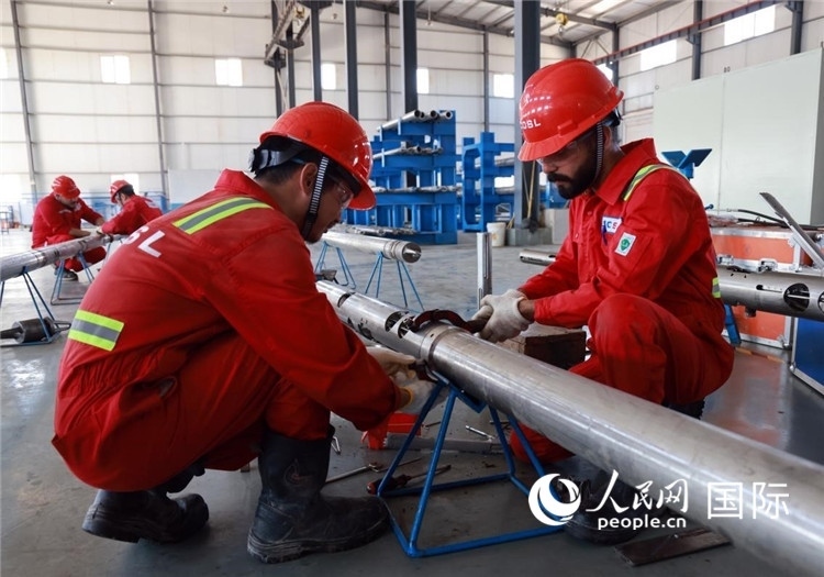 中伊員工共同在檢修鉆井設(shè)備。人民網(wǎng)記者管克江攝