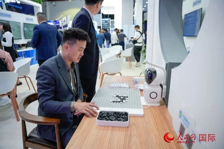 觀眾在中國移動(dòng)國際有限公司展臺(tái)體驗(yàn)智慧圍棋機(jī)器人。人民網(wǎng) 塔里克·易卜拉欣攝