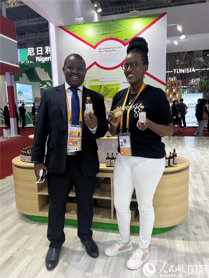 6月6日，布隆迪駐華大使館一等參贊布利馬索·阿爾弗雷德 (左，Bulimaso Alfred) 和參展商卡馬里扎·埃斯特拉 (Kamariza Estella) 在第七屆中國國際進(jìn)口博覽會(huì)布隆迪館展示當(dāng)?shù)厣a(chǎn)的辣木油。（人民網(wǎng) 艾里士 攝）