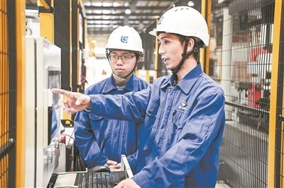 在廣西柳工機(jī)械股份有限公司生產(chǎn)車間內(nèi)，一名高級(jí)技師（右）給徒弟講解數(shù)控設(shè)備操作細(xì)節(jié)。新華社記者 曹祎銘攝