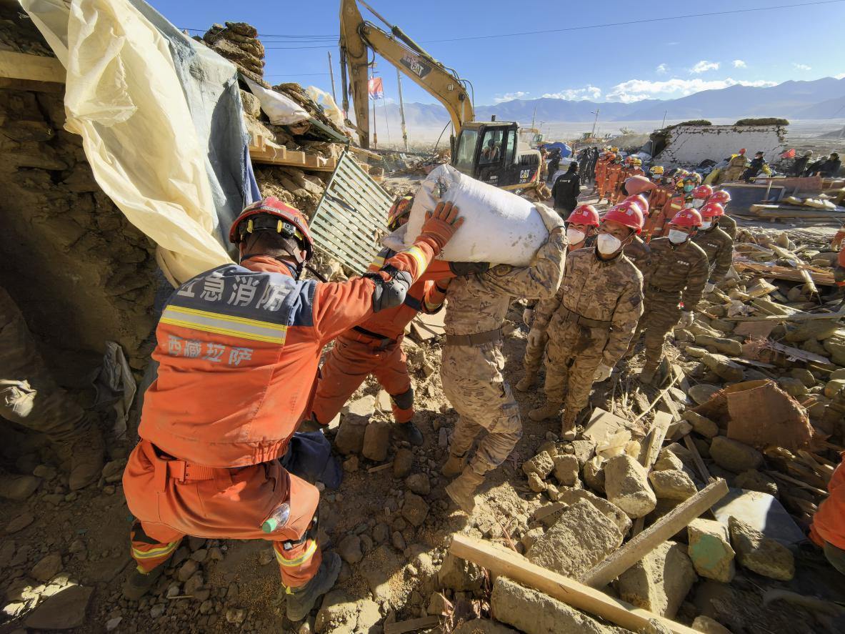 1月11日，定日縣長所鄉(xiāng)古榮村，應(yīng)急消防等救援人員排隊(duì)接力搶運(yùn)掩埋在倒塌房屋下的群眾財(cái)物。人民日報(bào)記者楊翹楚攝