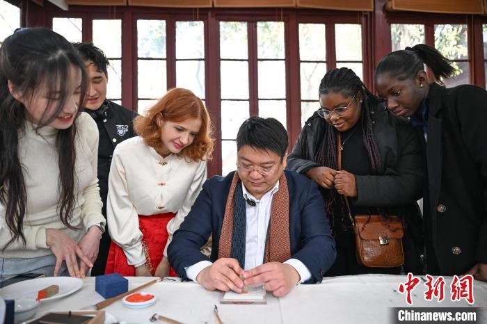 1月20日，篆刻家王臻向外籍留學(xué)生展示篆刻印章。當(dāng)日，來自巴西、馬來西亞、加納、哈薩克斯坦的外籍留學(xué)生在浙江杭州西泠印社體驗福貼、春聯(lián)和篆刻，感受古老的中國傳統(tǒng)文化。中新社記者 王剛 攝