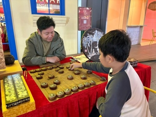 柯秋楓與市民下椰雕象棋。人民網(wǎng) 陳葉欣攝