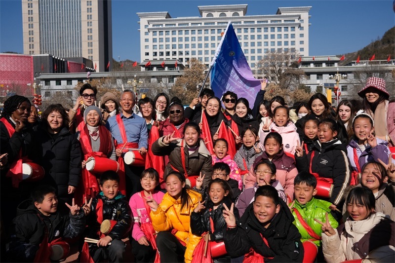 中外青年學(xué)子在安塞文化廣場觀看陜北腰鼓和大秧歌表演后合影留念，大家踏著鼓點(diǎn)共舞，翻飛的紅綢與躍動的身影交織，在黃土地廣場上繪出一幅生動的陜北民俗互動畫卷