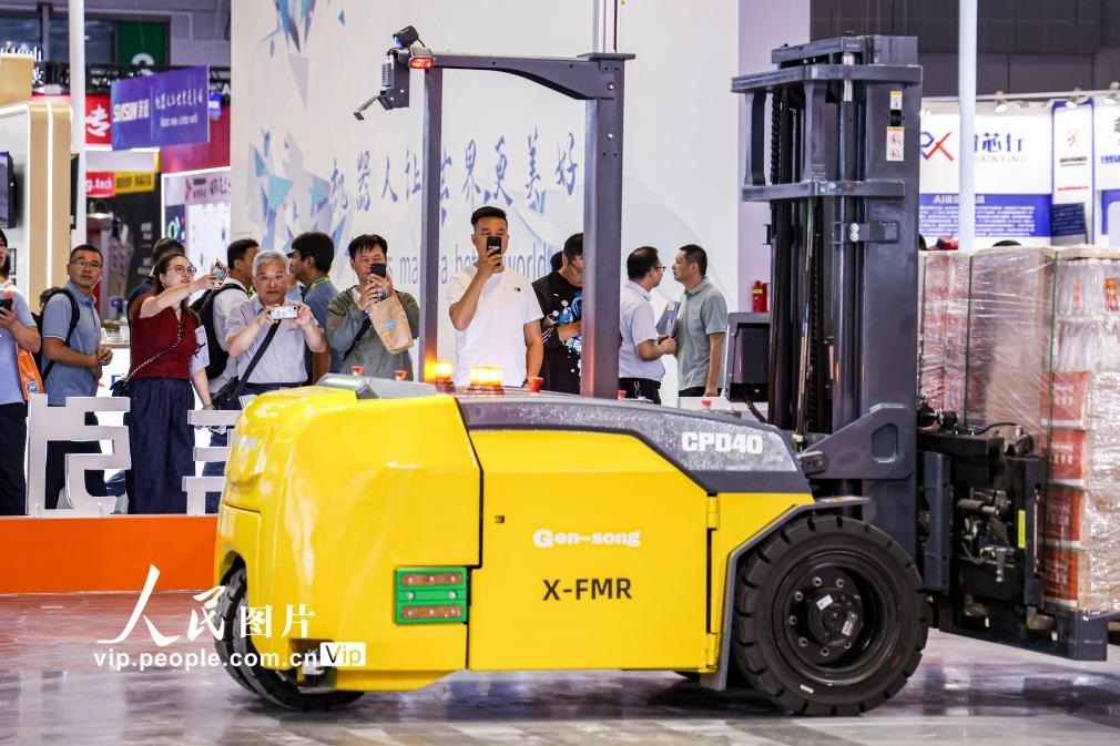 第24屆中國工博會現(xiàn)場，觀眾觀看叉取機(jī)器人作業(yè)演示。王初攝（人民圖片網(wǎng)）