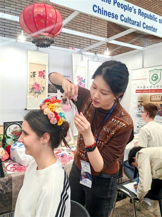 展覽正值羅馬尼亞迎春花節(jié)，國際中文教師志愿者潘婧穎向游客們介紹了國家非物質(zhì)文化遺產(chǎn)——福建泉州的簪花文化。布加勒斯特大學孔子學院供圖。