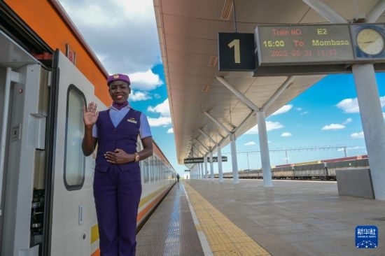 5月31日，在蒙內(nèi)鐵路內(nèi)羅畢站，一名乘務(wù)員在即將開往蒙巴薩的E2次列車旁等候乘客。新華社記者 楊光 攝